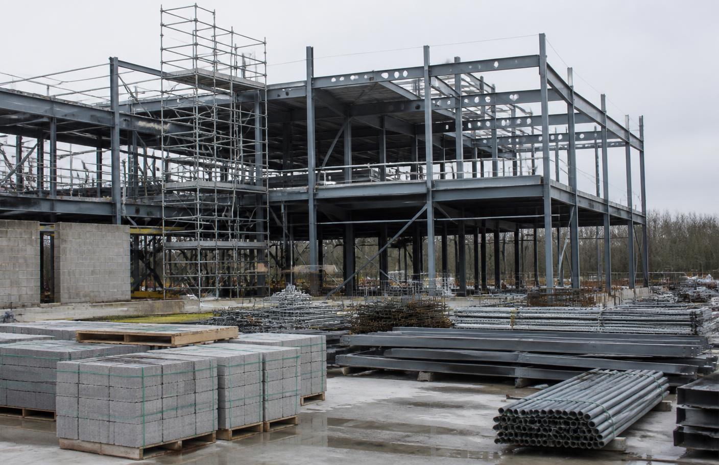 A steel-framed commercial building under construction with materials stacked on the slab